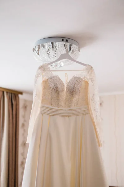 Vestido de novia muy hermoso de la novia colgando en la lámpara de araña en la habitación . —  Fotos de Stock