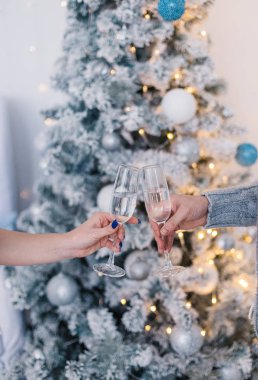 Bir erkek ve bir kadın bardak şampanya Noel ağacı arka plan üzerinde tutuyor.