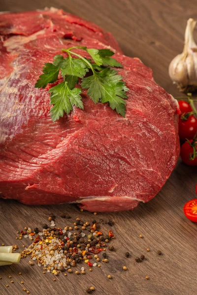 Raw beef on a wooden background with spices and vegetables. — Stock Photo, Image