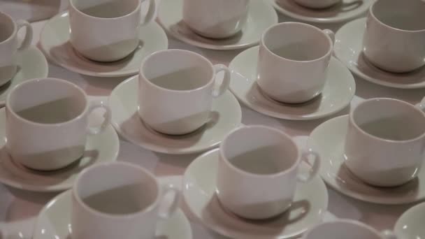 В ресторане на столе стоят белые чашки и тарелки ранжированы. Много чашек . — стоковое видео