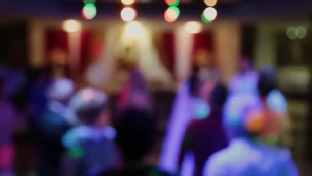 Imagens desfocadas de uma festa lotada de loucos com pessoas dançando na pista de dança, acenando com as mãos, sentindo-se incrível. Silhuetas masculinas e femininas atraentes revelam em raios de luz estroboscópicos — Vídeo de Stock