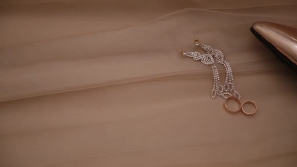 Свадебное золото женская обувь кольца и ювелирные изделия на кровати . — стоковое видео