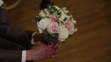 Adam bir buket dantel şeritler elinde tutuyor. Kasetleri rüzgarda geliştirmek. Güzel çiçekler damat tutar.