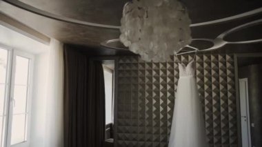 Güzel düğün elbisesi içinde büyük bir avize asılı.