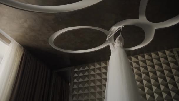 Belle robe de mariée suspendue dans un grand lustre . — Video