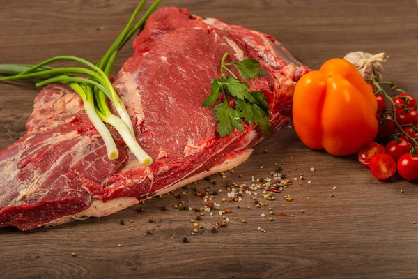 Rohes Rindfleisch auf Holzgrund mit Gewürzen und Gemüse. — Stockfoto