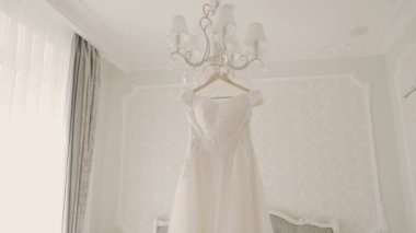 Güzel düğün elbisesi içinde büyük bir avize asılı.