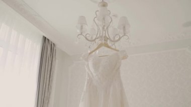 Güzel düğün elbisesi içinde büyük bir avize asılı.