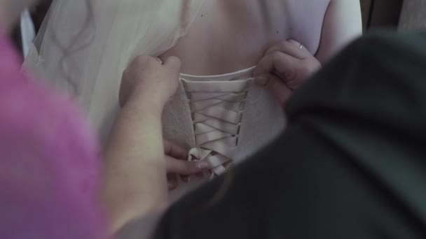 Zár-megjelöl-ból vissza a fiatal menyasszony esküvő készül. Anya lánya menyasszonyi ruha öltöztetős. Csipke és éves női kezek közelről. Valós időben teljes hd videó felvétel — Stock videók