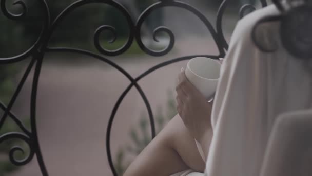 Vacker kvinna dricka kaffe på balkongen i ett gammalt hus. — Stockvideo