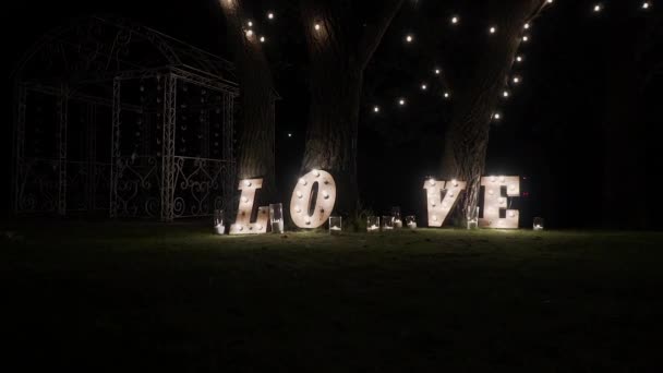 Letras de madera con bombillas. Palabra - Amor. Palabra iluminada AMOR en el escenario. Palabra de amor que consiste en luces en el piso brillante — Vídeo de stock