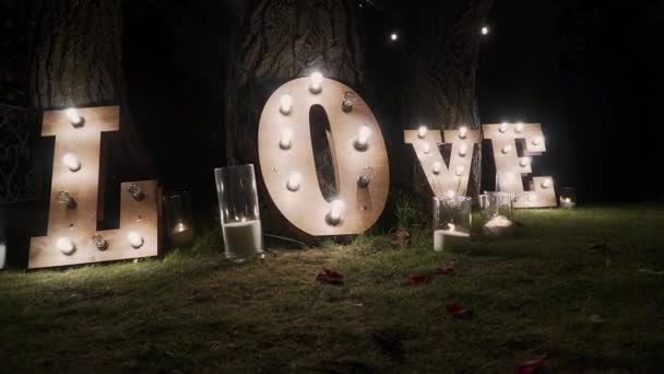 Wooden letters with bulb lights. Word - Love. Illuminated word LOVE on the stage. Word love consisting of lights on glossy floor — Stock Video