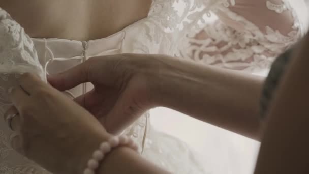 Close up of back of young bride getting ready for wedding ceremony. Mother helping her daughter to dress up bridal dress. Close up of lace and aged female hands. Real time full hd video footage — Stock Video