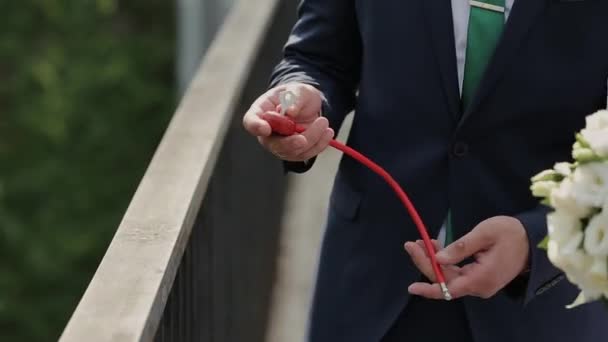 Hochzeitssymbol, Schloss in den Händen von Braut und Bräutigam. Frischvermählte befestigen das Schloss an der Brücke als Symbol der Liebe. Vorhängeschloss in den Händen des Brautpaares. Herzförmige Verriegelung am Geländer der Brücke — Stockvideo