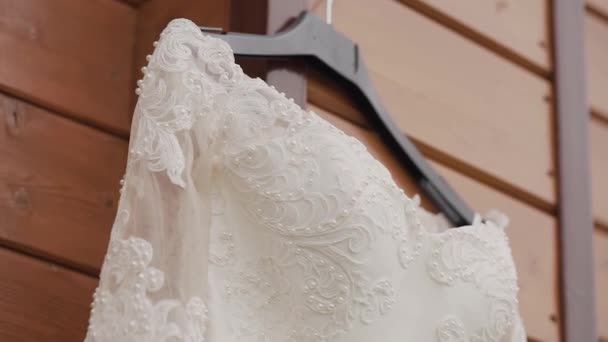 Beautiful wedding dress hanging on a wooden house. — Stock Video