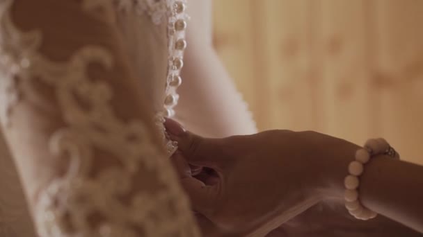 Detail zadní části mladá nevěsta připravuje na svatební obřad. Matka pomáhá její dcera zdobit svatební šaty. Detailní záběr z krajky a věku ženských rukou. Full hd video záznam v reálném čase