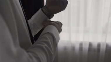 Mavi takım elbiseli başarılı adam kollarını yakın çekim düzeltiyor.