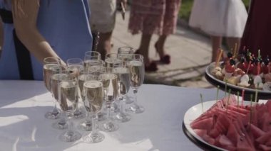 Şampanya, meyve ve kanepeler gözlüklü büfe masa. Kadın bir kadeh şampanya ve bir aperatif tablosundan alır.