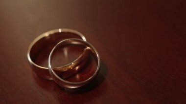 Bej renkli arka plan üzerinde altın nişan yüzük. Nikah yüzükleri. İki muhteşem Alyans Düğün gününde. Masada iki Alyans