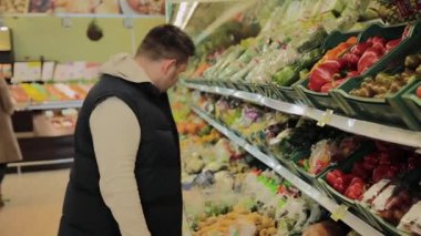 Süpermarkette şişman adam kendi için meyve seçer.