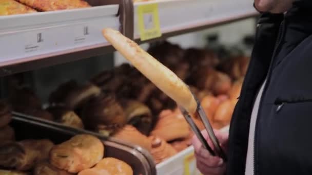Man in een supermarkt kiest gebak voor zichzelf. — Stockvideo