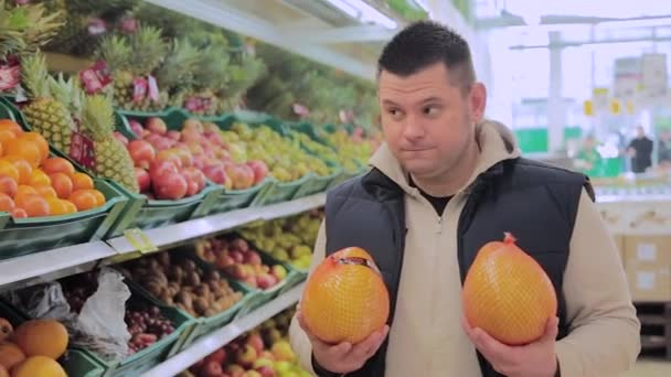 Gordo no supermercado escolhe frutas para si mesmo . — Vídeo de Stock