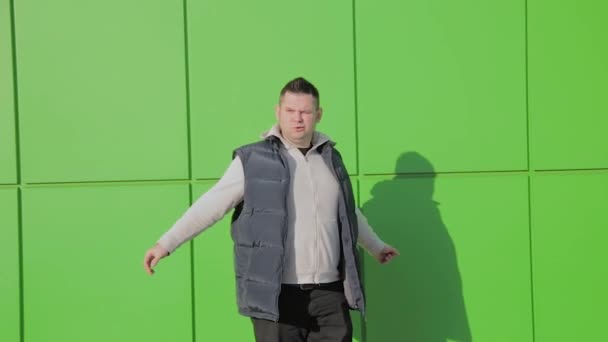 Dicker Mann posiert vor einer grünen Wand in der Nähe des Ladens. — Stockvideo