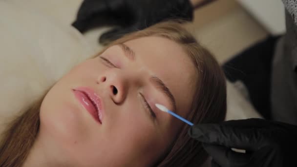 Une très belle fille dans un salon de beauté fait une plastification des cils. Esthéticienne effectue la procédure de fragmentation des cils . — Video