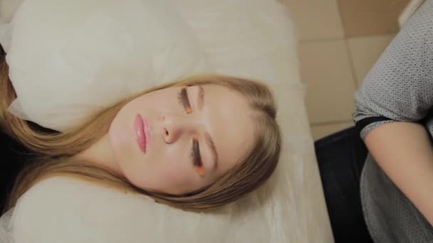 Een zeer mooi meisje in een schoonheidssalon heeft een lamineren wimpers. Wachten op lijm op wimpers te drogen — Stockvideo