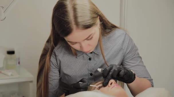 A very beautiful girl in a beauty salon does a lamination lashes. Beautician performs the procedure eyelash fragmentation. — Stock Video