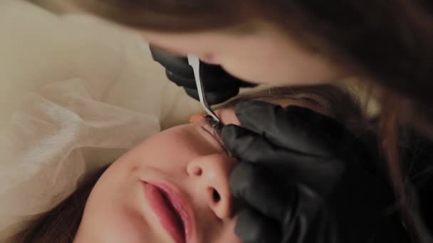 一个非常漂亮的女孩在美容院做层压睫毛。美容师执行睫毛碎片的程序. — 图库视频影像