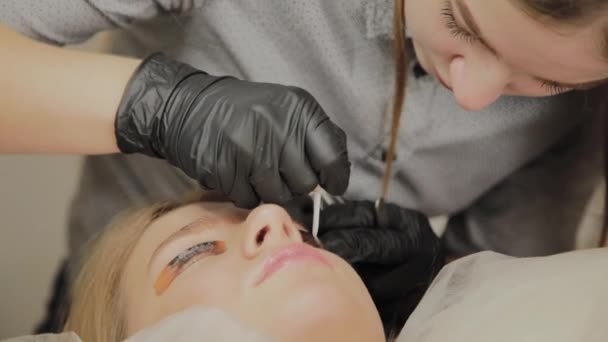 Une très belle fille dans un salon de beauté fait une plastification des cils. Esthéticienne effectue la procédure de fragmentation des cils . — Video