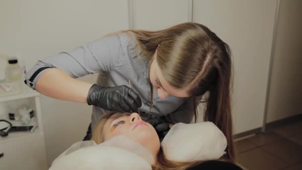 一个非常漂亮的女孩在美容院做层压睫毛。美容师执行睫毛碎片的程序. — 图库视频影像