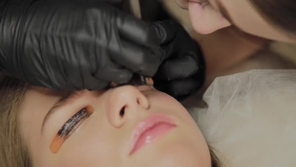 A very beautiful girl in a beauty salon does a lamination lashes. Beautician performs the procedure eyelash fragmentation. — Stock Video