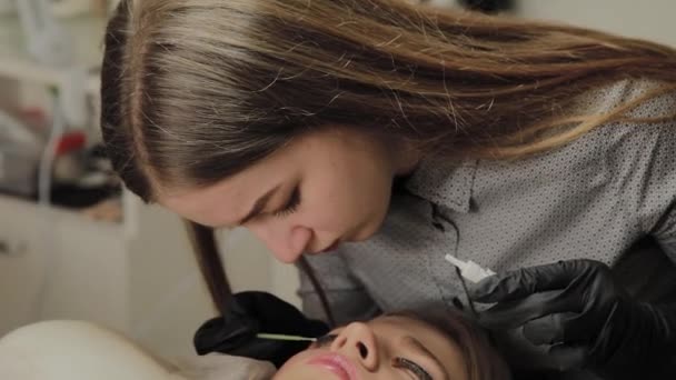 A very beautiful girl in a beauty salon does a lamination lashes. Beautician performs the procedure eyelash fragmentation. — Stock Video