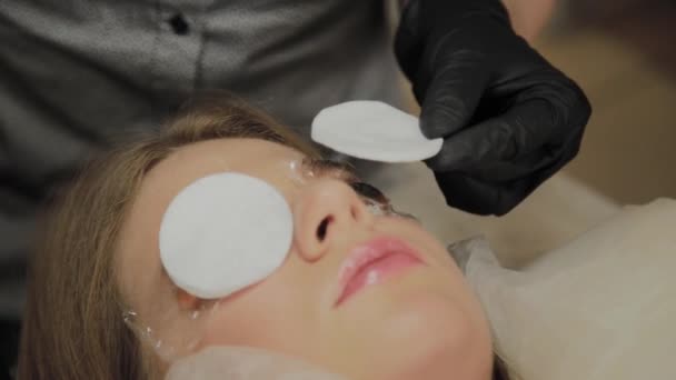 A very beautiful girl in a beauty salon does a lamination lashes. Beautician performs the procedure eyelash fragmentation. — Stock Video