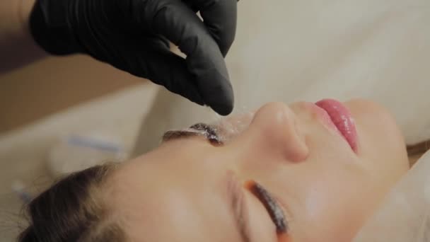 Une très belle fille dans un salon de beauté fait une plastification des cils. Esthéticienne effectue la procédure de fragmentation des cils . — Video