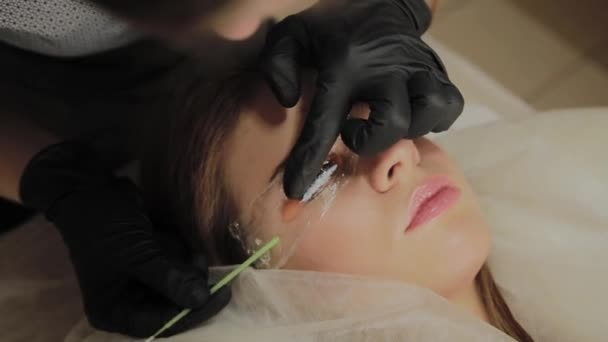 A very beautiful girl in a beauty salon does a lamination lashes. Beautician performs the procedure eyelash fragmentation. — Stock Video