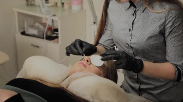 En mycket vacker flicka i en Skönhets Salong gör en laminering fransar. Kosmetolog utför förfarandet ögonfransar fragmentering. — Stockvideo