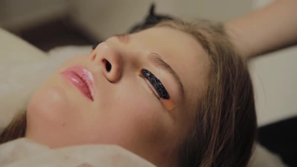 En mycket vacker flicka i en Skönhets Salong gör en laminering fransar. Liggande väntar torkning måla på ögonfransarna. — Stockvideo