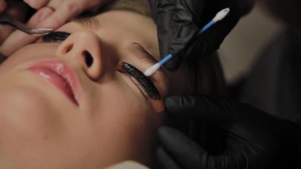 Ein sehr schönes Mädchen in einem Schönheitssalon macht eine Laminierung Wimpern. Kosmetikerin führt den Eingriff Wimpernfragmentierung durch. — Stockvideo