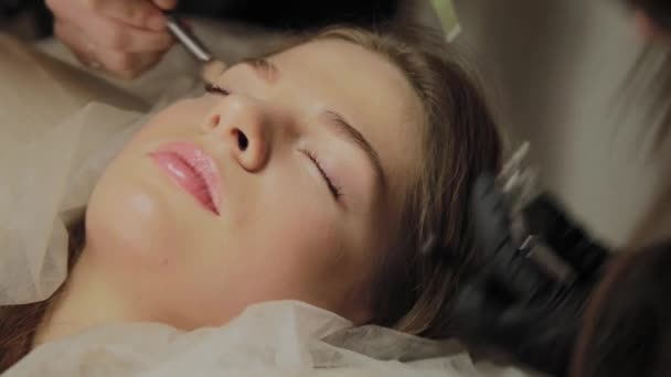 Une très belle fille dans un salon de beauté fait une plastification des cils. Esthéticienne effectue la procédure de fragmentation des cils . — Video