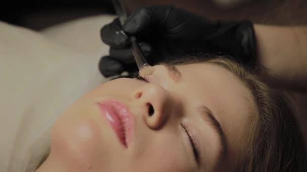 Une très belle fille dans un salon de beauté fait une plastification des cils. Esthéticienne effectue la procédure de fragmentation des cils . — Video