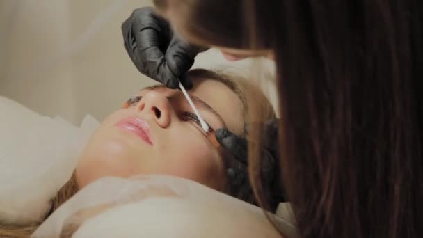 Une très belle fille dans un salon de beauté fait une plastification des cils. Esthéticienne effectue la procédure de fragmentation des cils . — Video