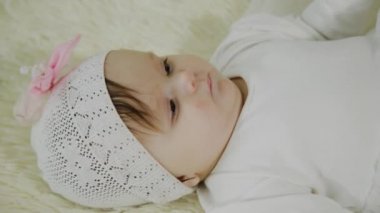 Güzel küçük kız beyaz yatakta yatıyor.