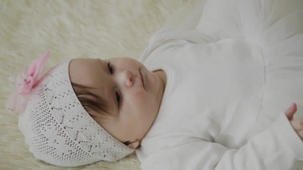 Красива маленька дівчинка лежить на білому ліжку . — стокове відео