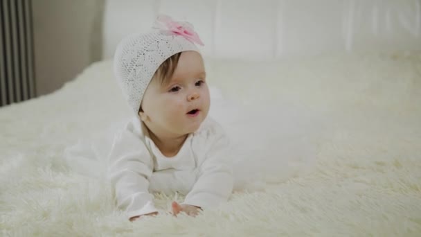 Красива маленька дівчинка лежить на білому ліжку . — стокове відео