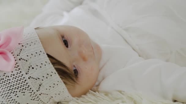 Menina bonita está deitada em uma cama branca e brincando com um brinquedo — Vídeo de Stock