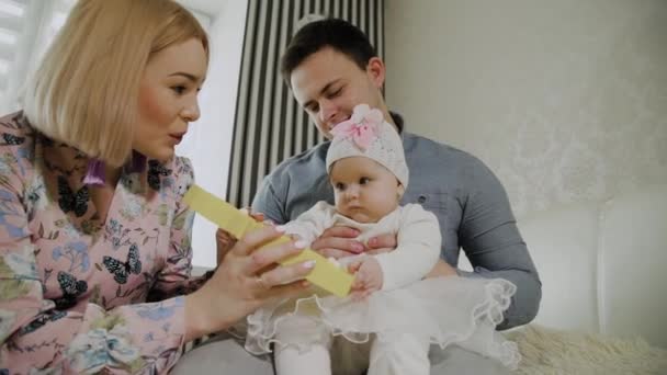 Gelukkige familie spelen met hun kleine dochter op een wit bed. — Stockvideo