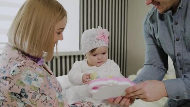 Gelukkige familie spelen met hun kleine dochter op een wit bed. — Stockvideo